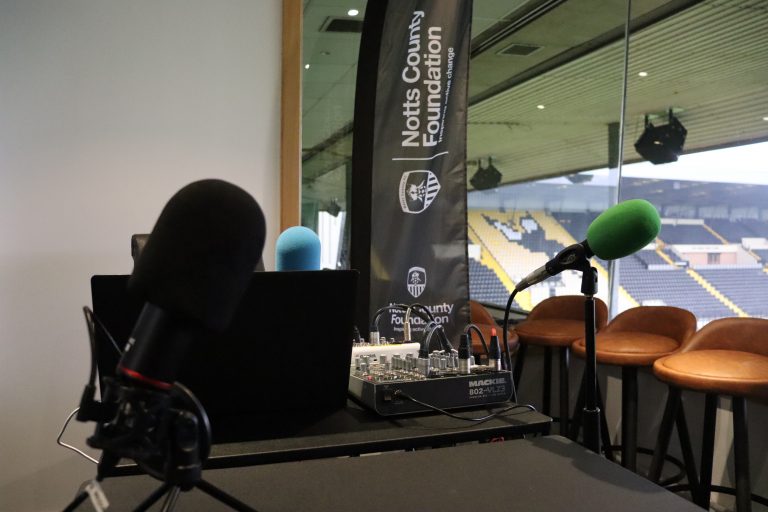 Meadow Lane's hospitality box hosts the NCF podcast, with a branded flag, two microphones and chairs all present in the photo.